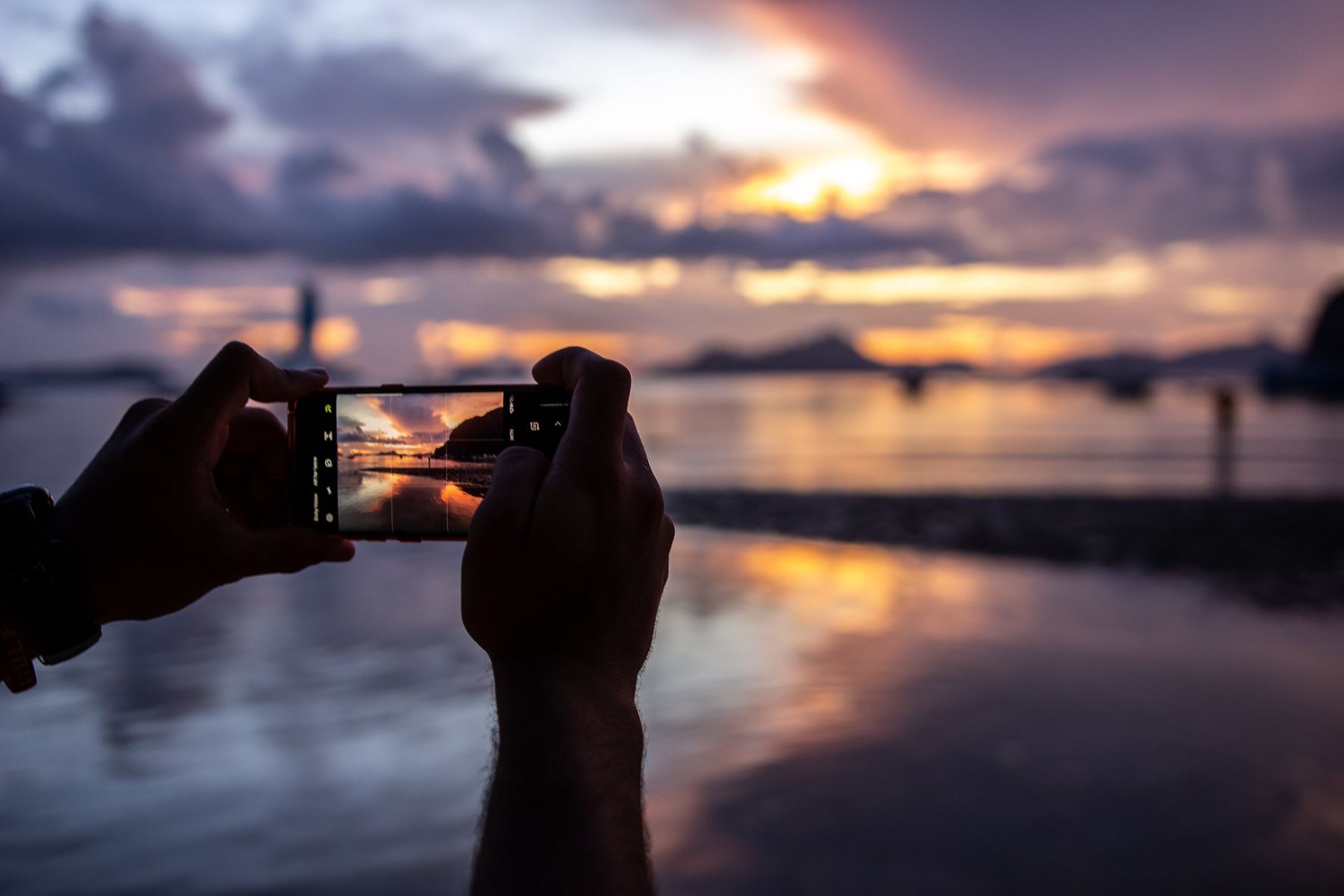 Mensch fotografiert Sonnenuntergang mit dem Handy